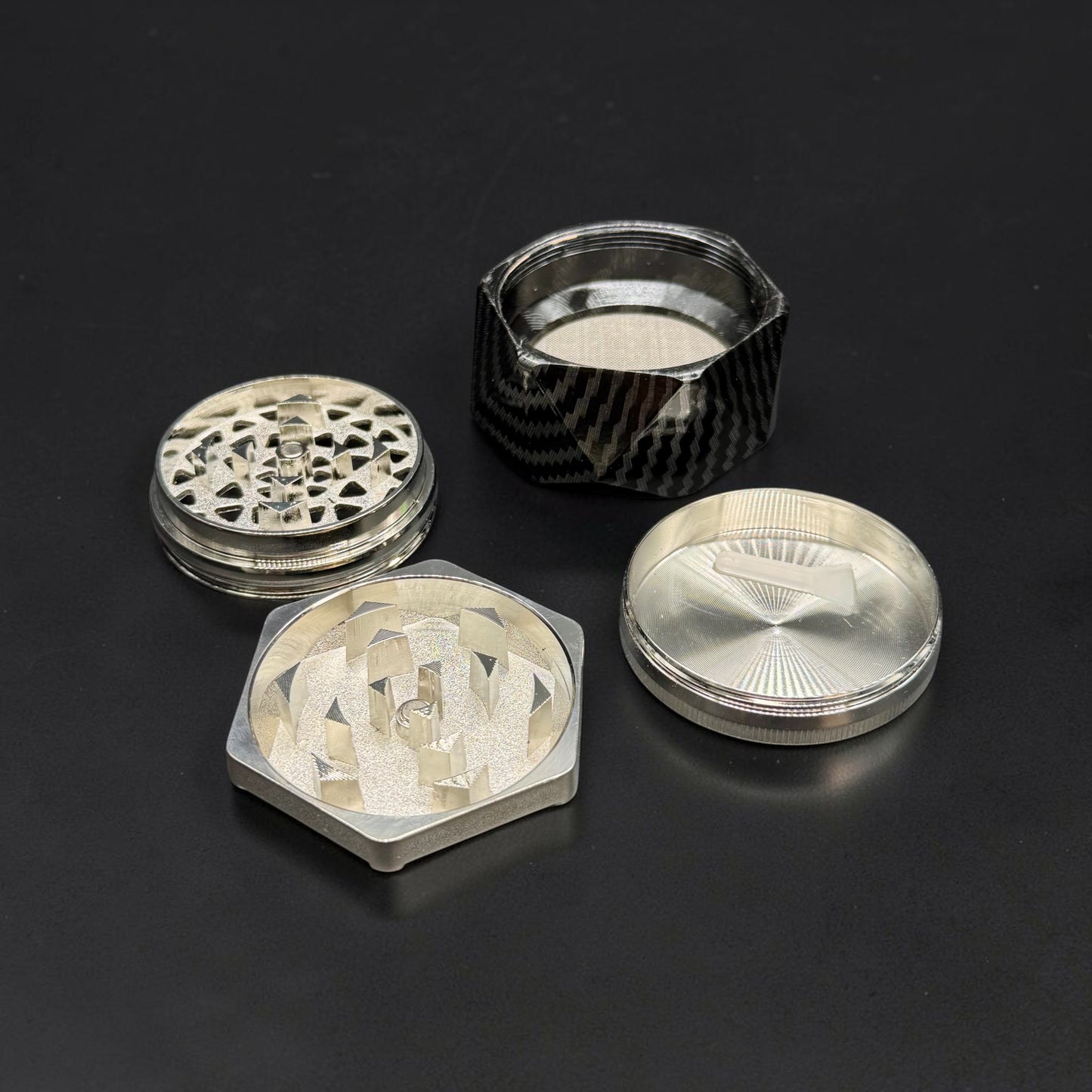 Set of four metallic grinders on a black background