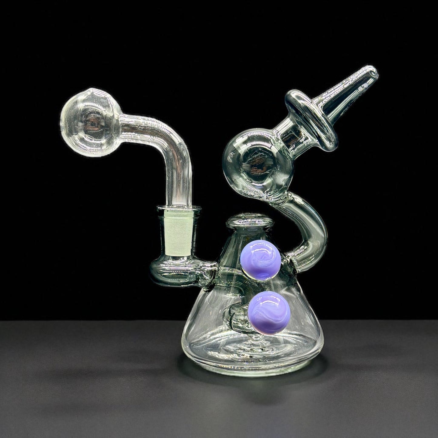 Glass smoking device with purple balls on a black background
