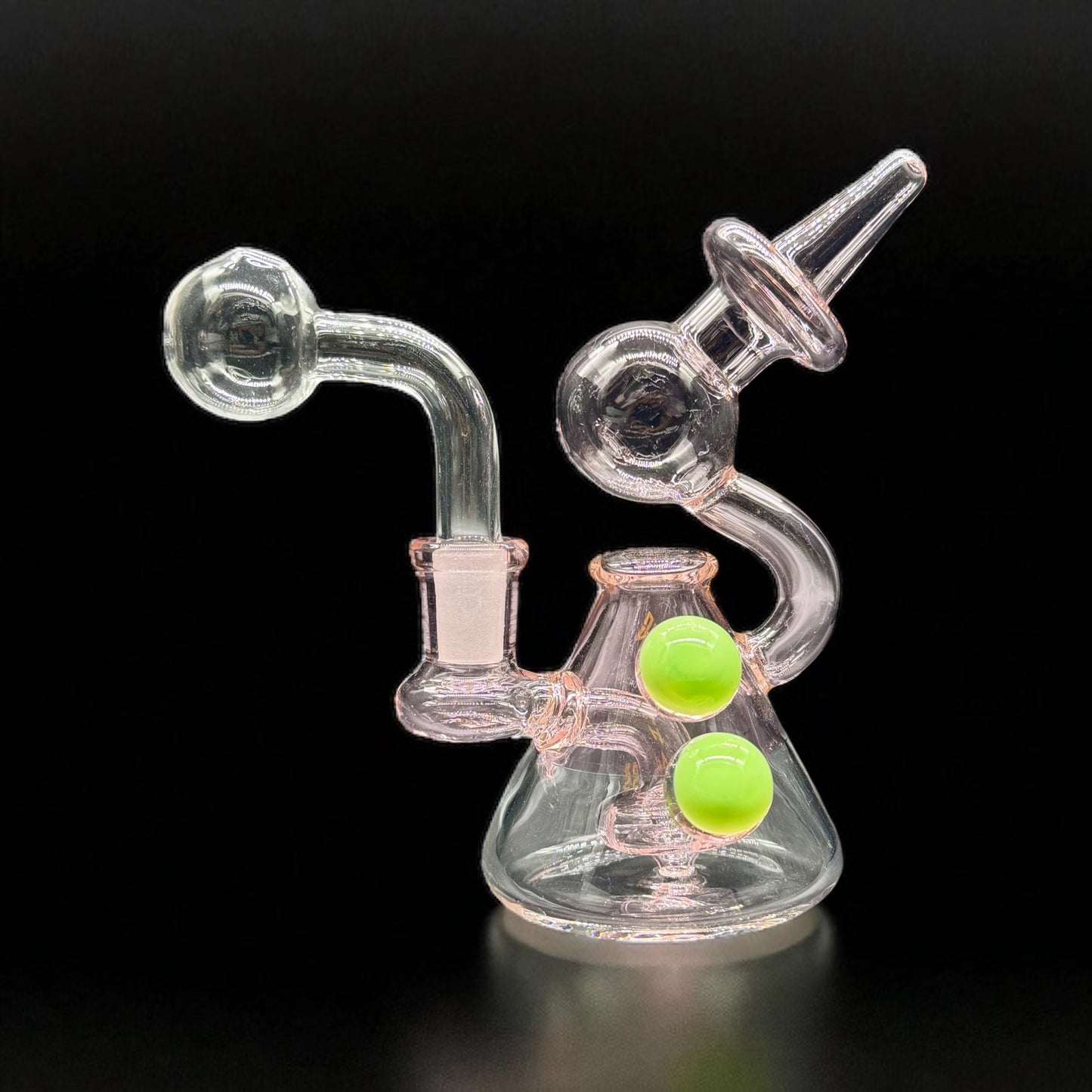 Clear glass smoking device with green balls on a black background