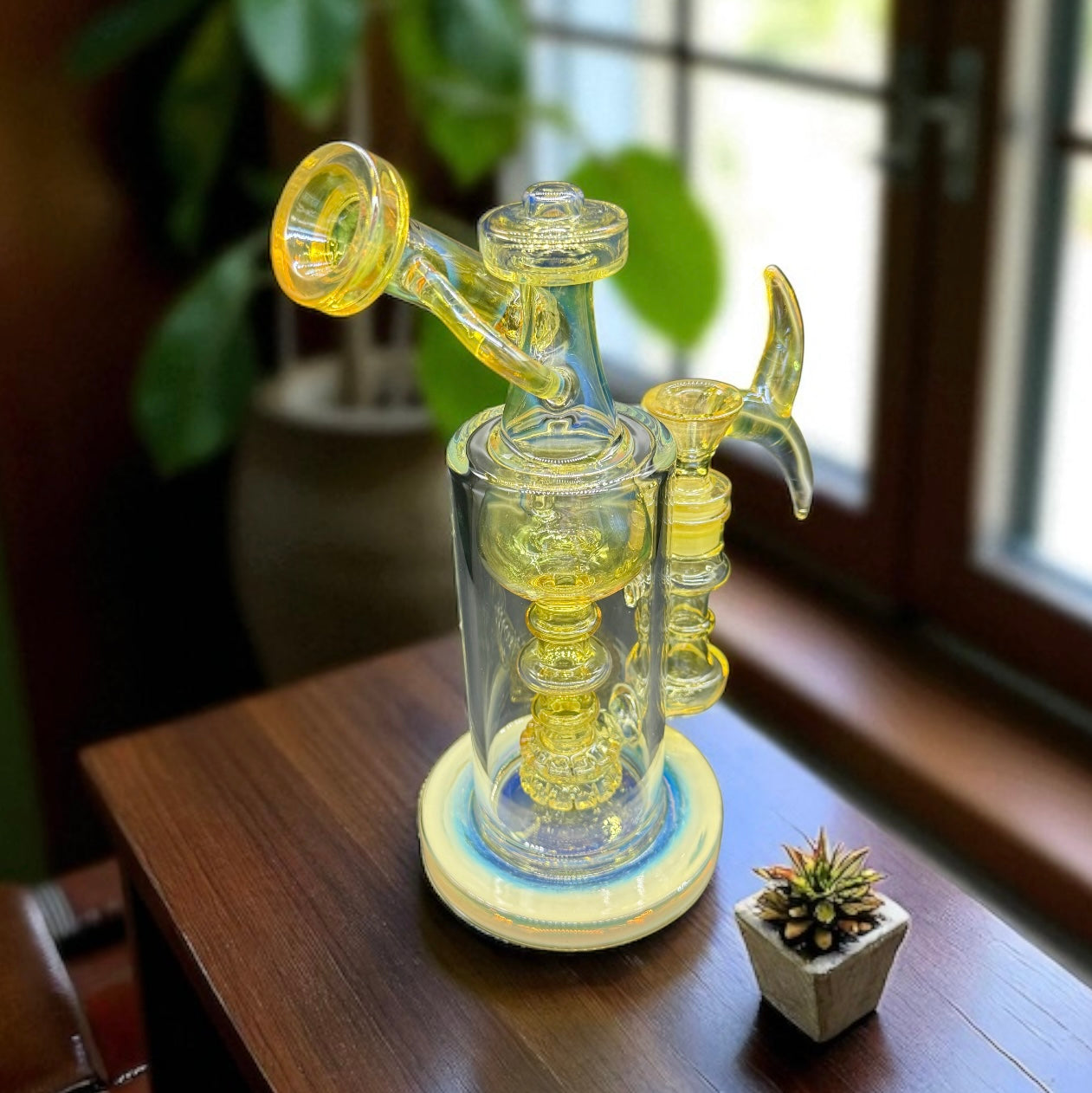 Glass smoking device with yellow accents on a wooden surface near a window