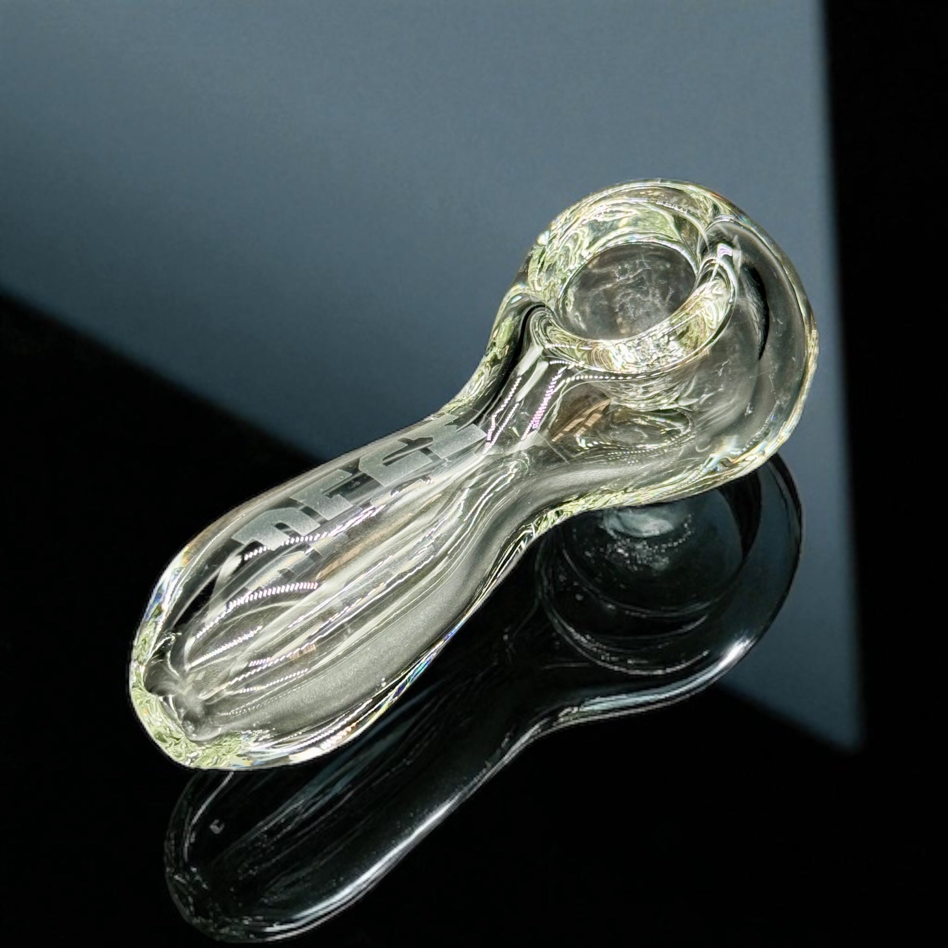 Clear glass pipe on a black stand with a dark background