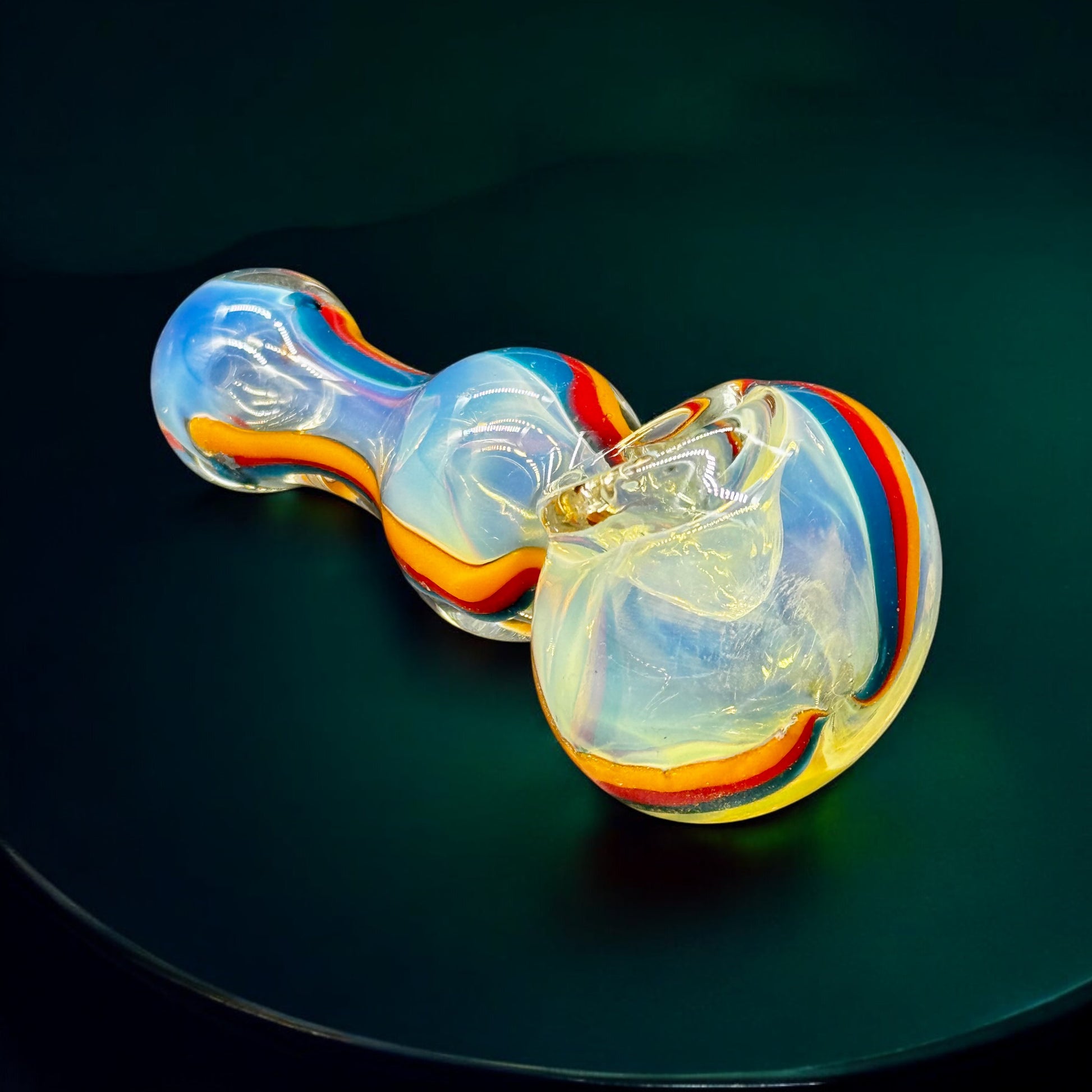 Underside of fumed glass pipe with glowing iridescent finish and smooth contour.