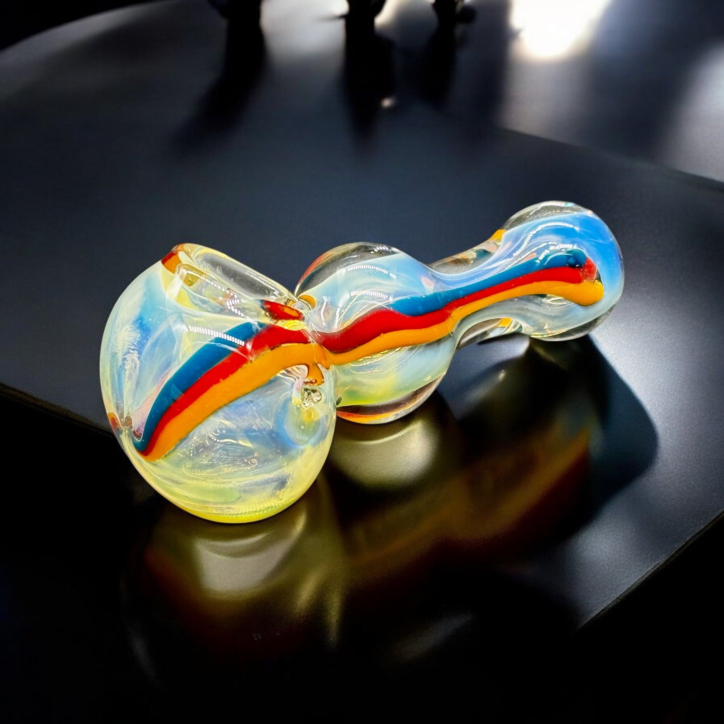 Side view of 4-inch hand-blown glass pipe with red, orange, and blue swirls.