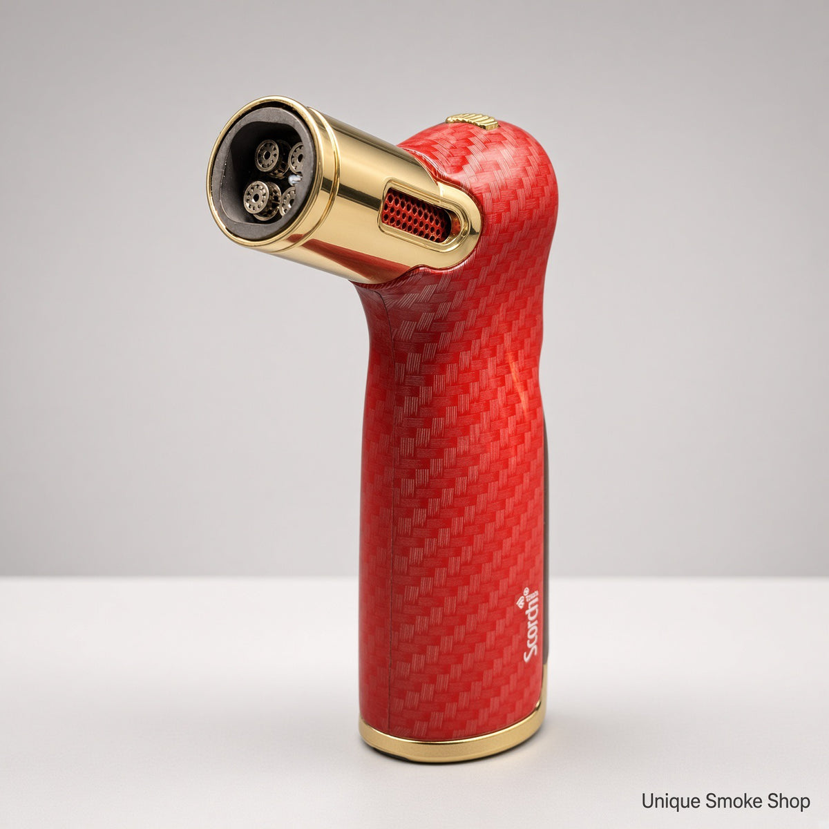A red carbon fiber torch lighter with gold accents, standing upright on a white surface against a light gray background. The brand name 'Scalpers' is visible on the side.