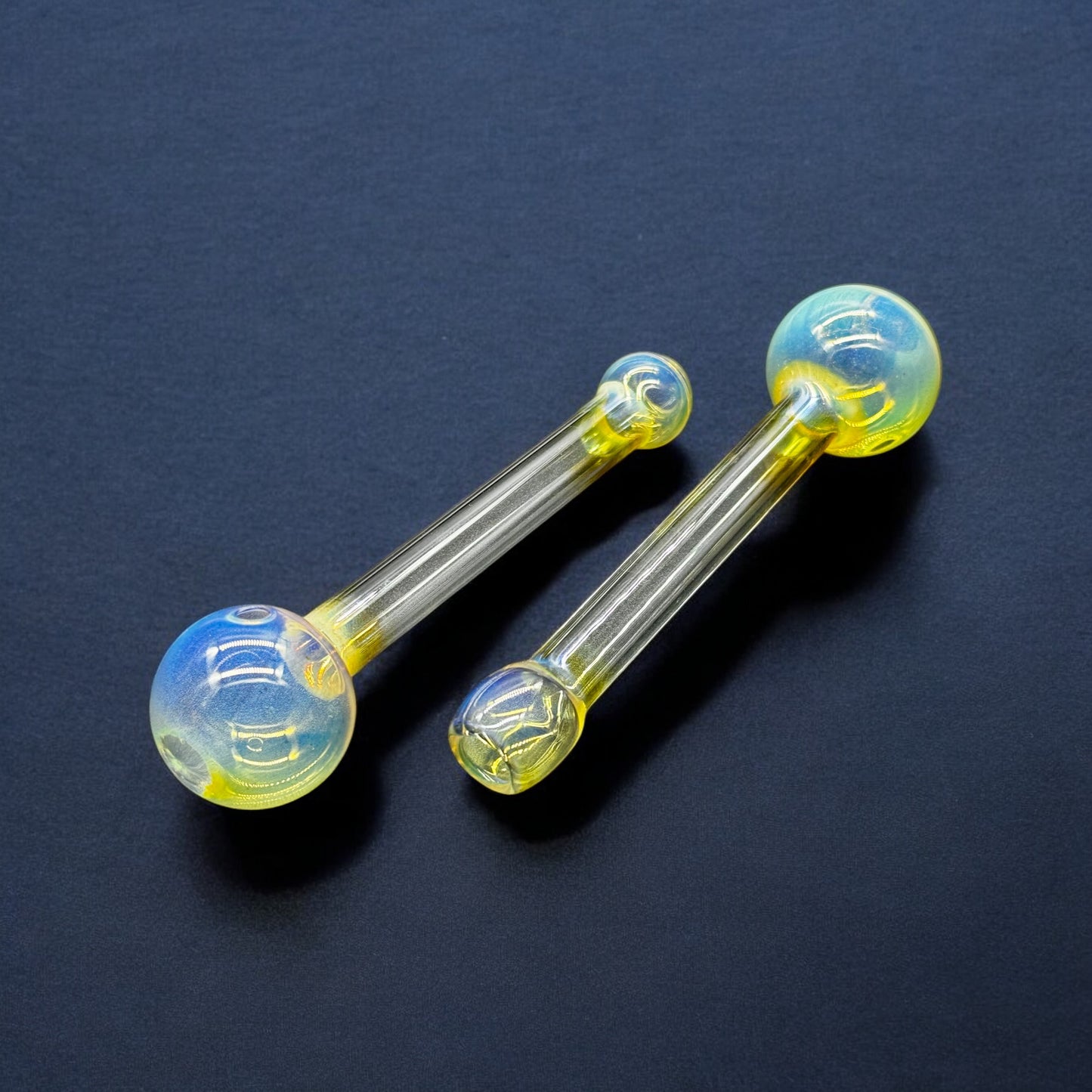 Two 5-inch fumed Pyrex glass oil burner pipes on black background – yellow and blue iridescent finish