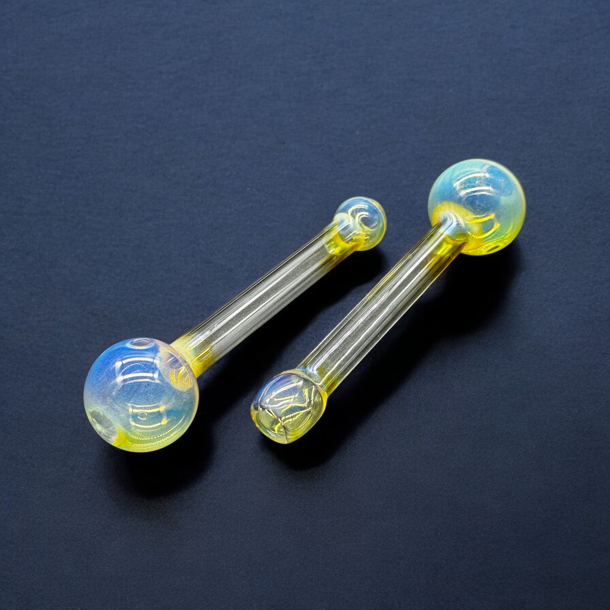 Two 5-inch fumed Pyrex glass oil burner pipes on black background – yellow and blue iridescent finish