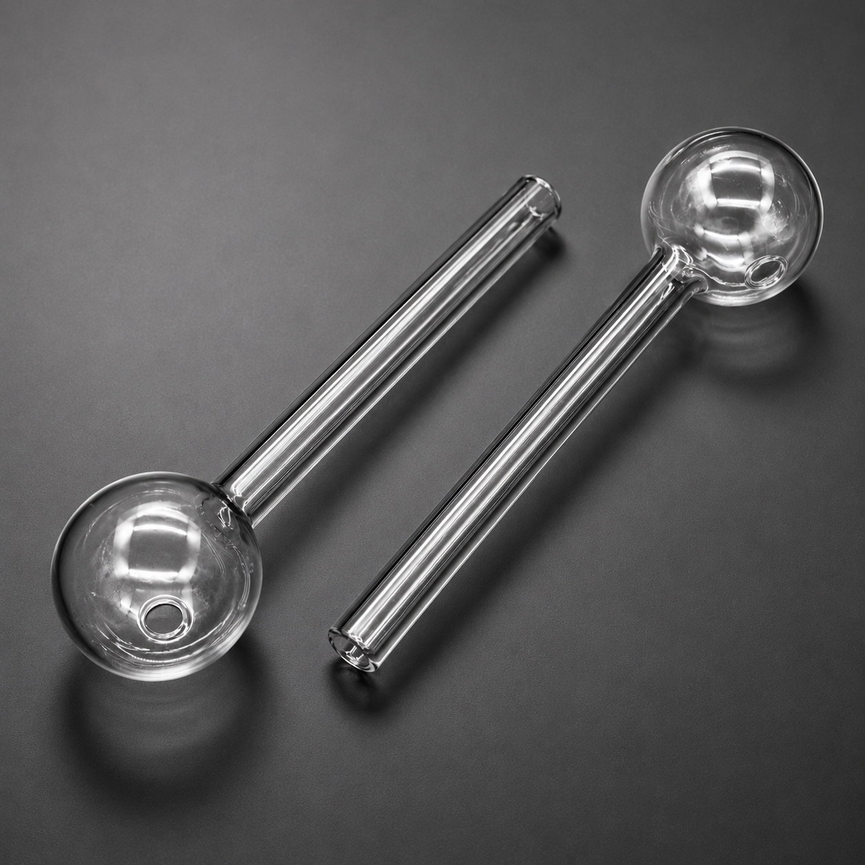 Two clear glass pipes on a dark gray background