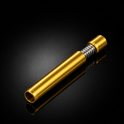 A metallic gold cylindrical component with a silver coiled spring near one end, photographed on a glossy black reflective background.