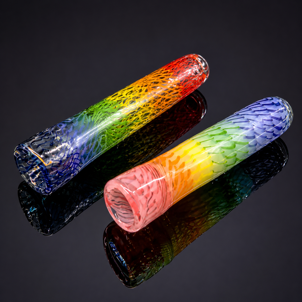 Two colorful glass pipes on a reflective black surface with a dark background