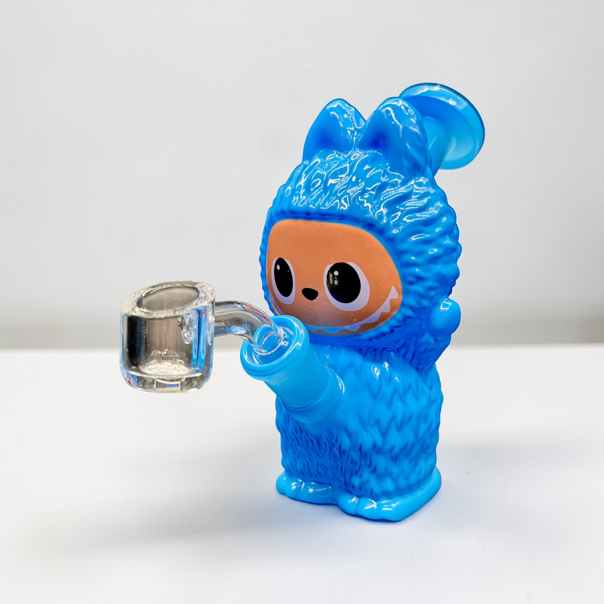 Blue creature figurine holding a glass mug on a white background