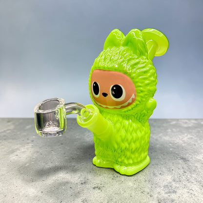 Green character holding a clear glass object on a gray surface with a light blue background