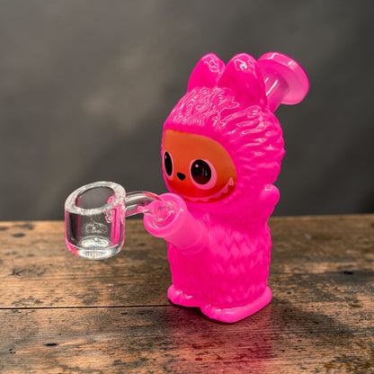 Pink cartoon character holding a clear glass mug on a wooden surface with a dark background