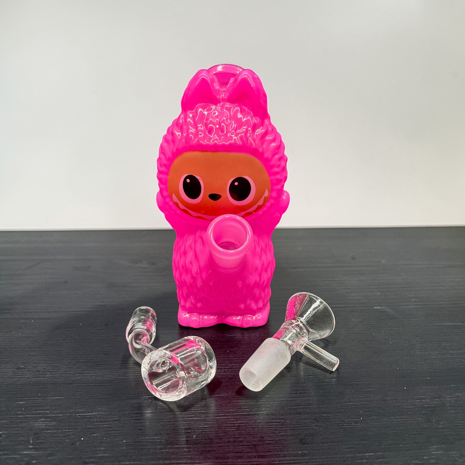 Pink character-shaped bottle with clear components on a dark surface