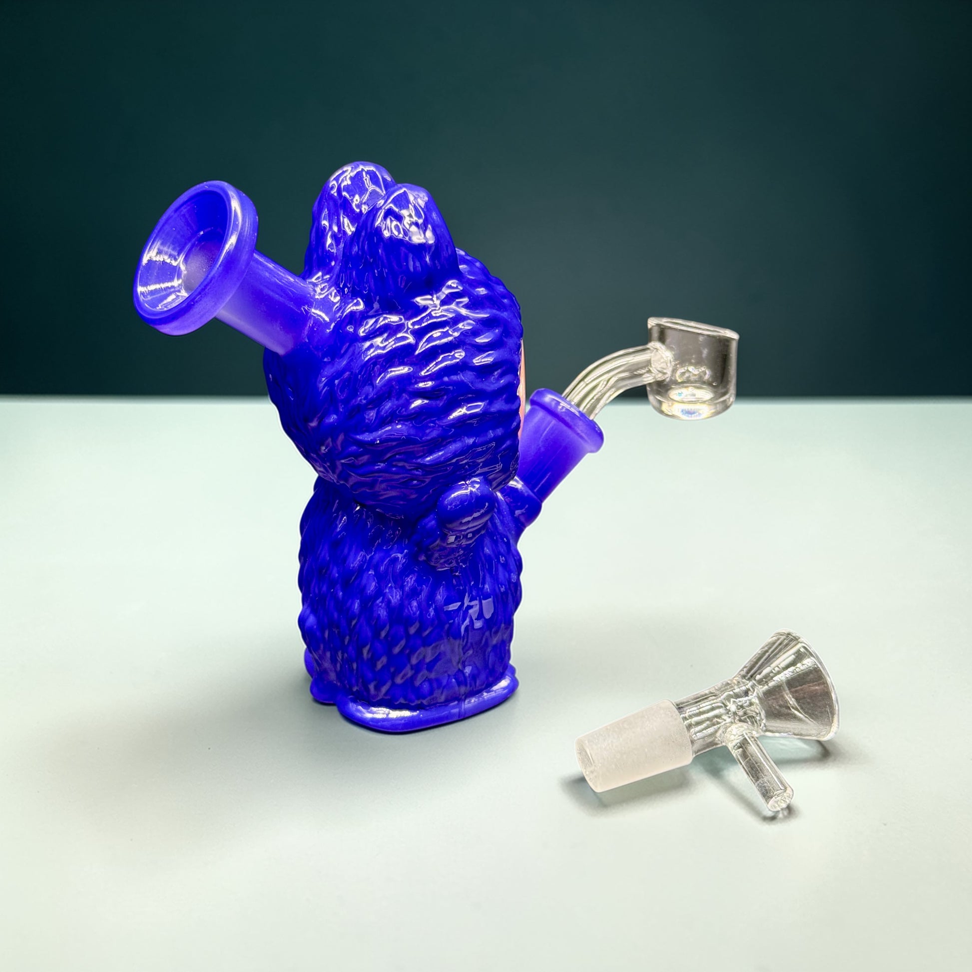 Blue glass smoking device with two attachments on a light gray surface.