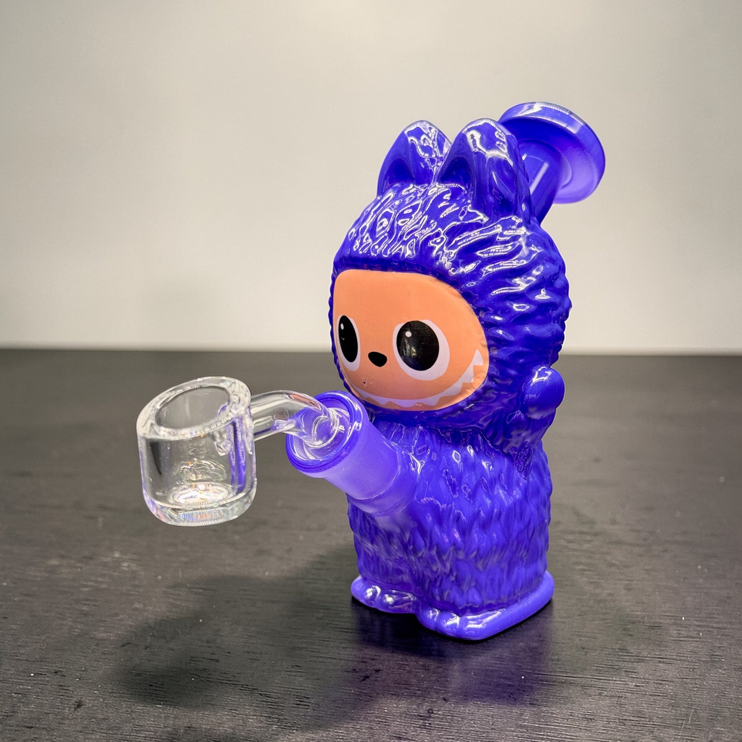 Purple glass figure with a clear mug on a dark surface