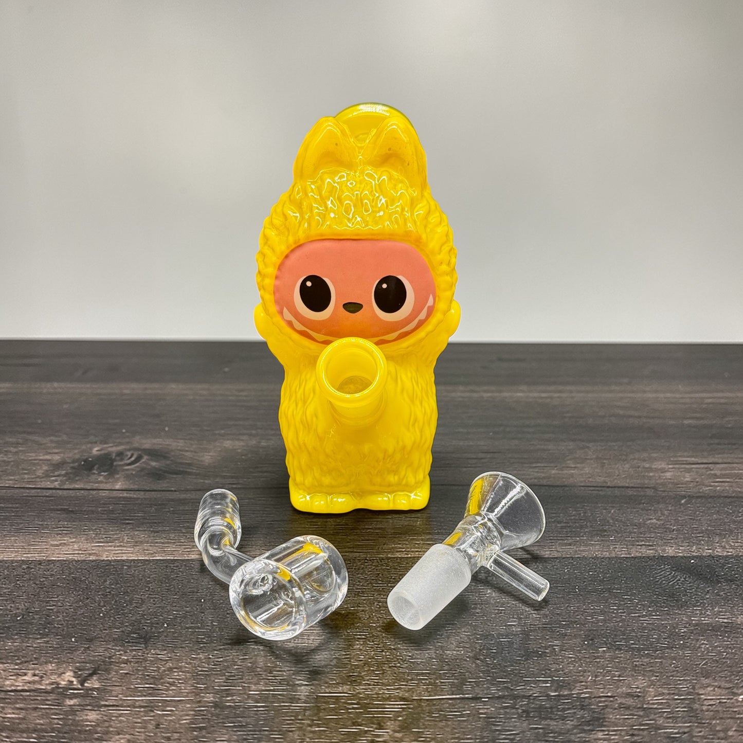 Yellow character-shaped bottle with clear nozzles on a wooden surface