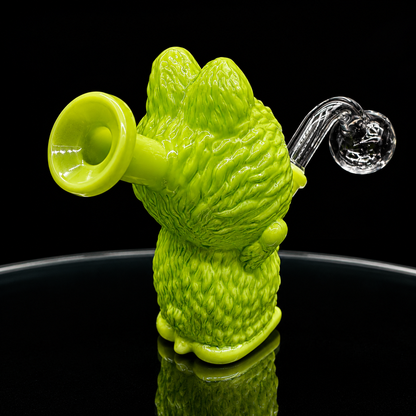 Green glass smoking accessory shaped like a bear on a black background