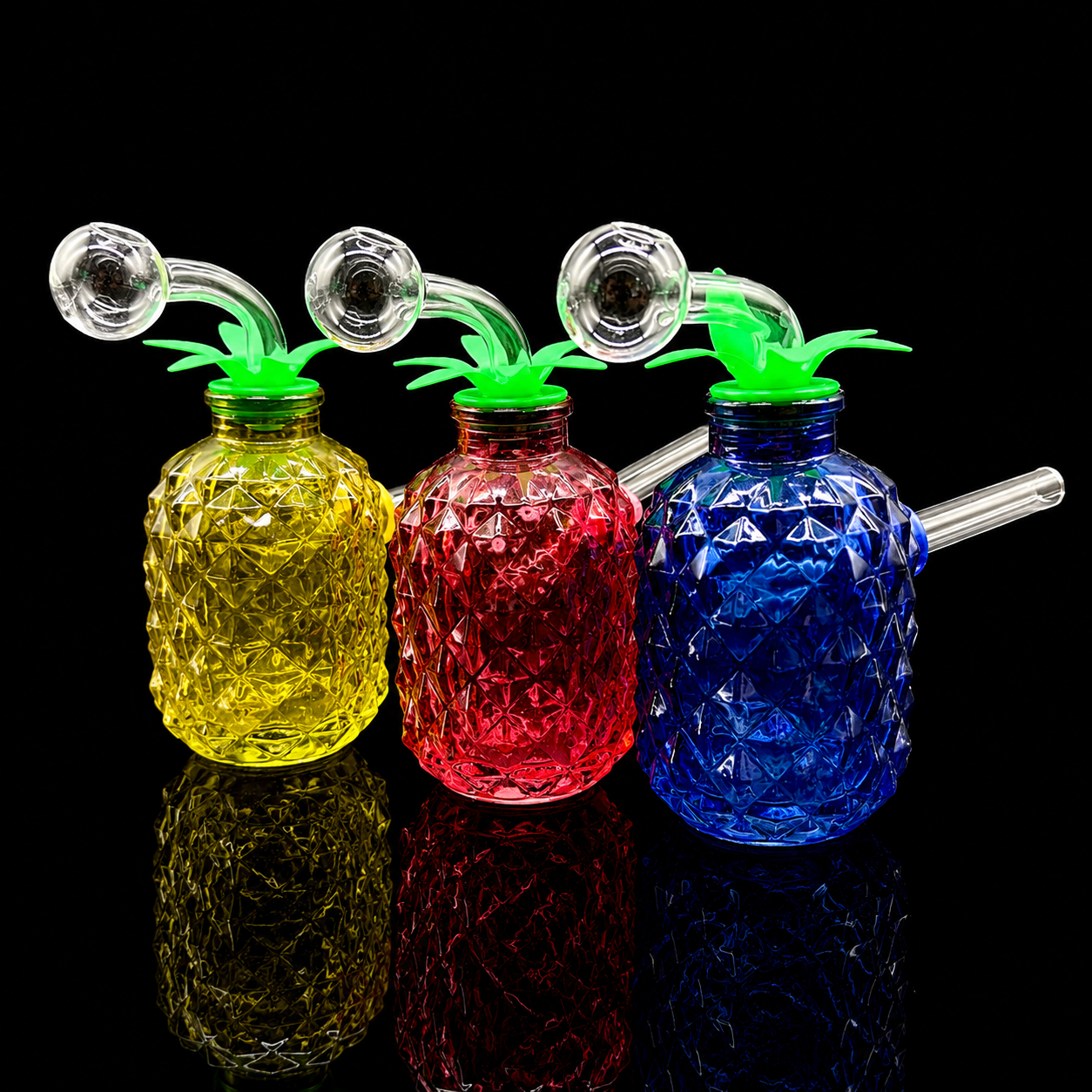 Three colorful pineapple-shaped glass drink containers with straws on a black background