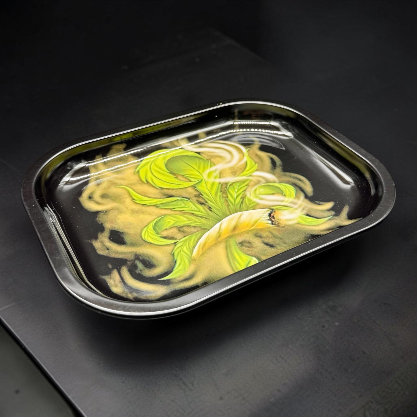 Metallic tray with artistic green design on a dark surface