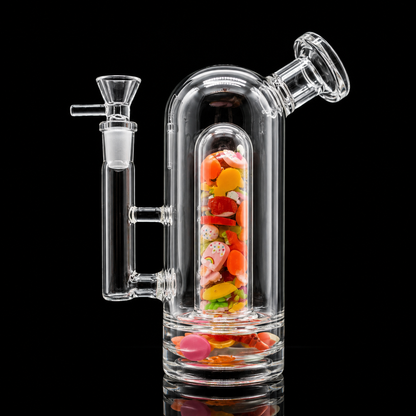 Clear glass smoking device with colorful candies inside on a black background