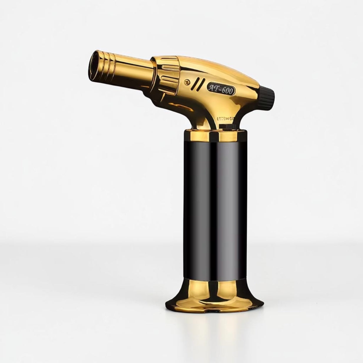 Gold and black butane torch on a white background