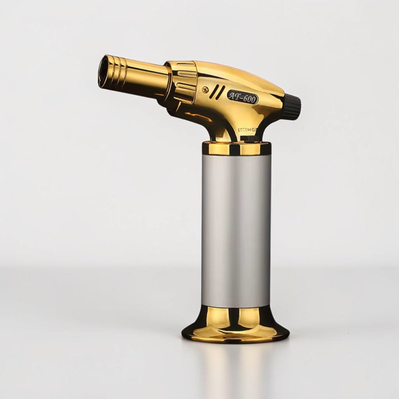 Gold and silver butane torch on a light gray background