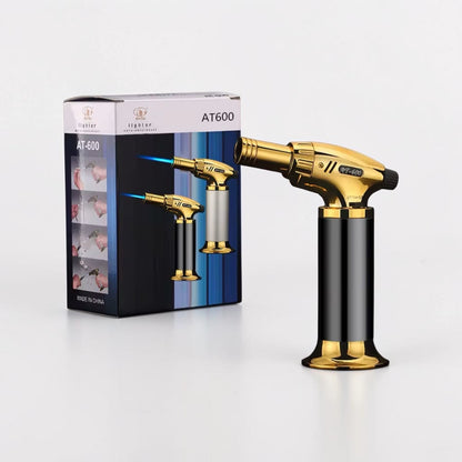 Gold and black butane torch with packaging on a white background