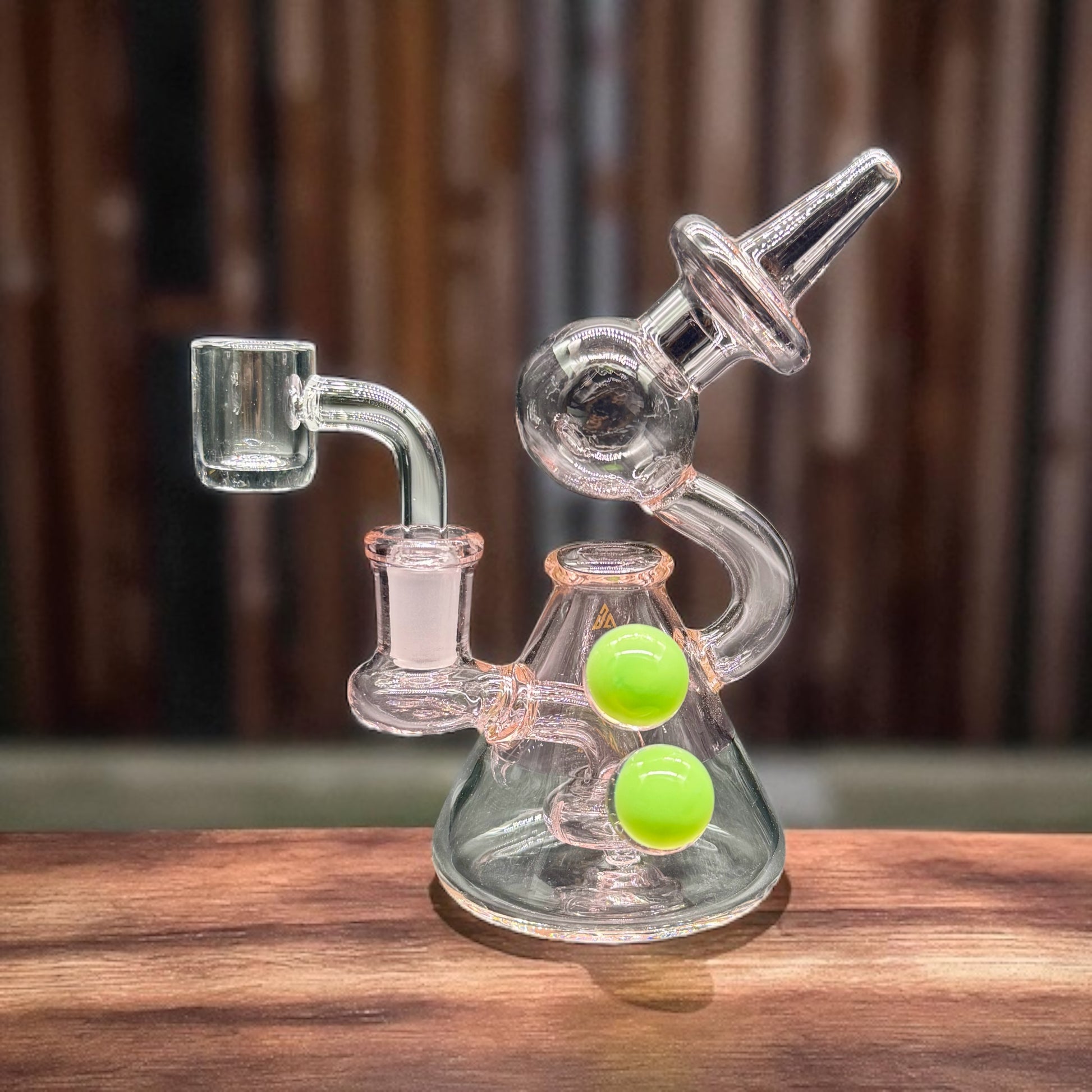 Glass smoking device with green balls on a wooden surface