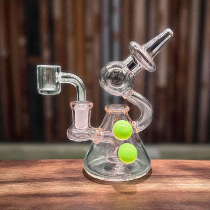 Glass smoking device with green balls on a wooden surface