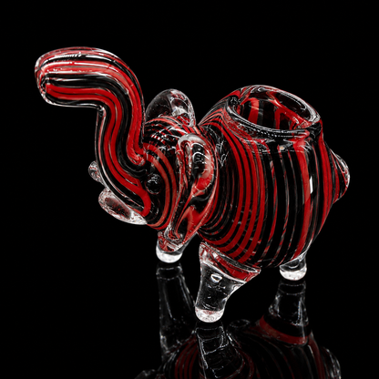 Glass sculpture of a ram with red and black patterns on a black background