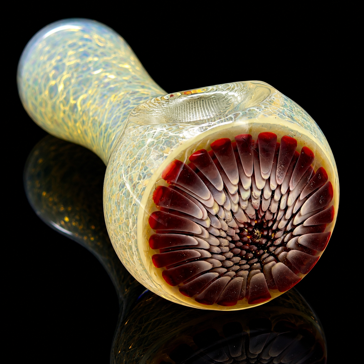 Glass smoking pipe with textured design on a reflective black surface
