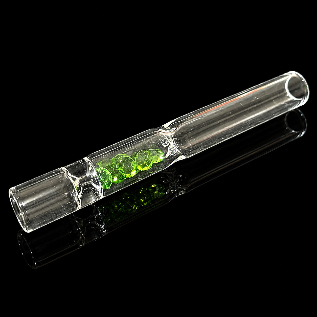 Clear glass pipe with green substance on a black background