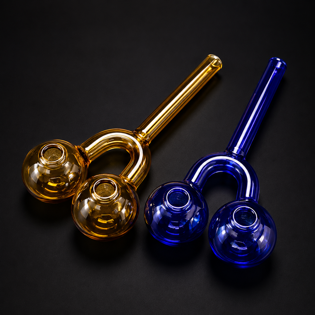 Two glass smoking accessories, one gold and one blue, on a black background.
