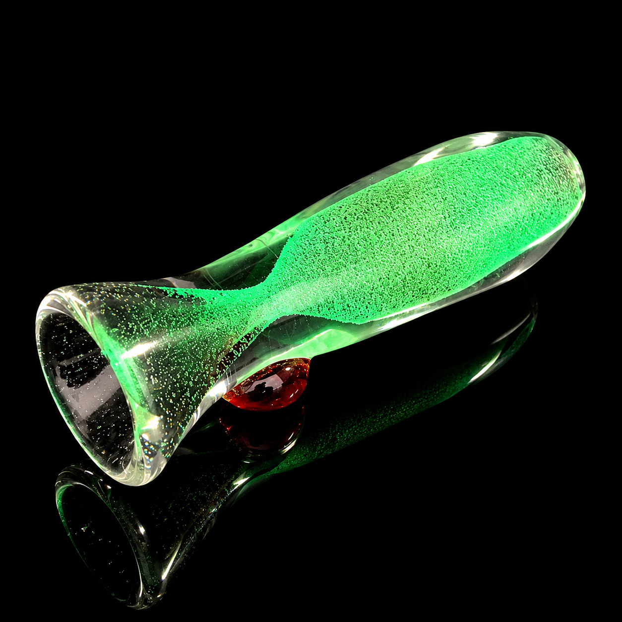 Green glass object with a textured surface on a black background