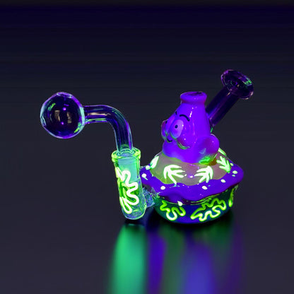 Glowing purple and green glass smoking device on a black background