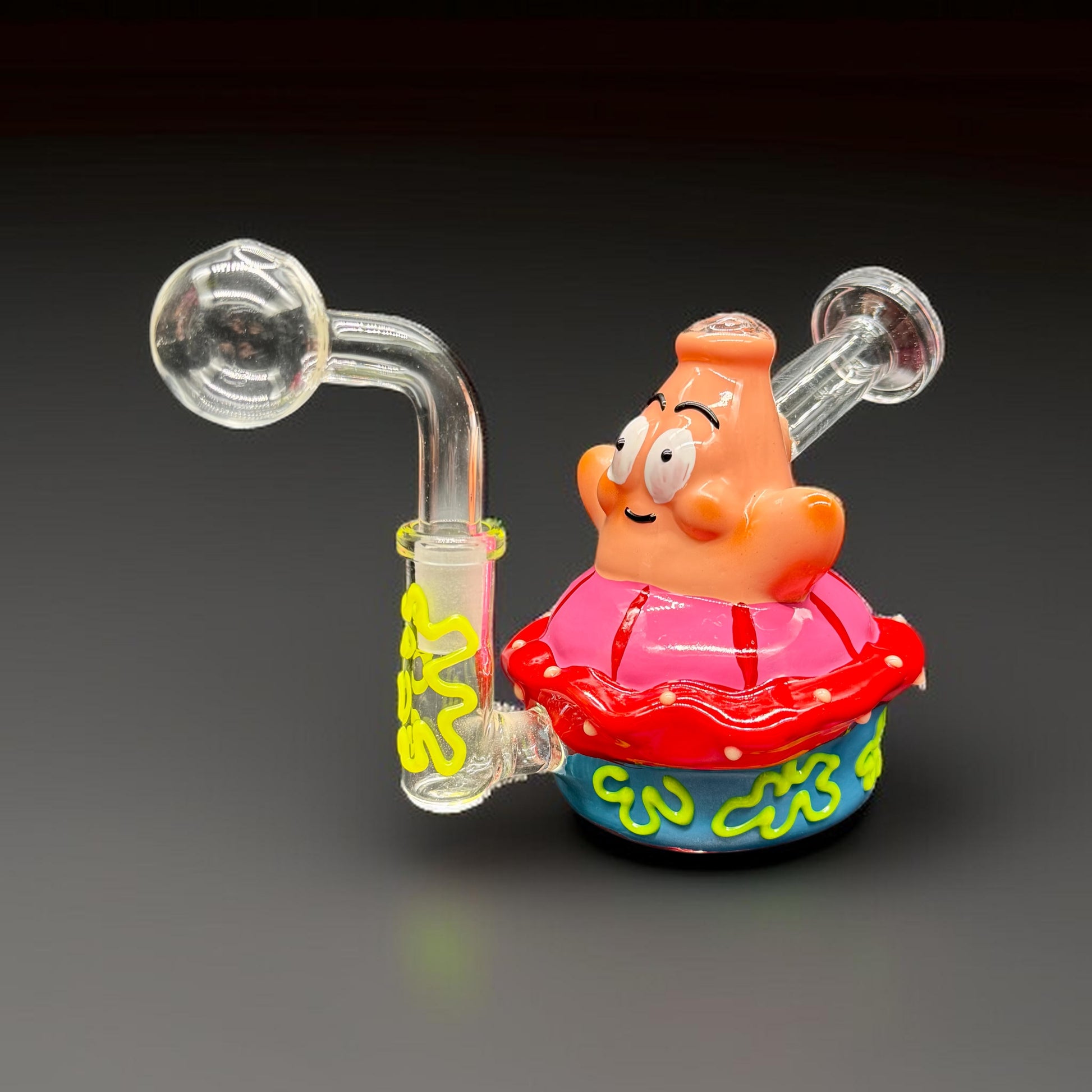 Colorful glass smoking device shaped like a cartoon character on a dark background