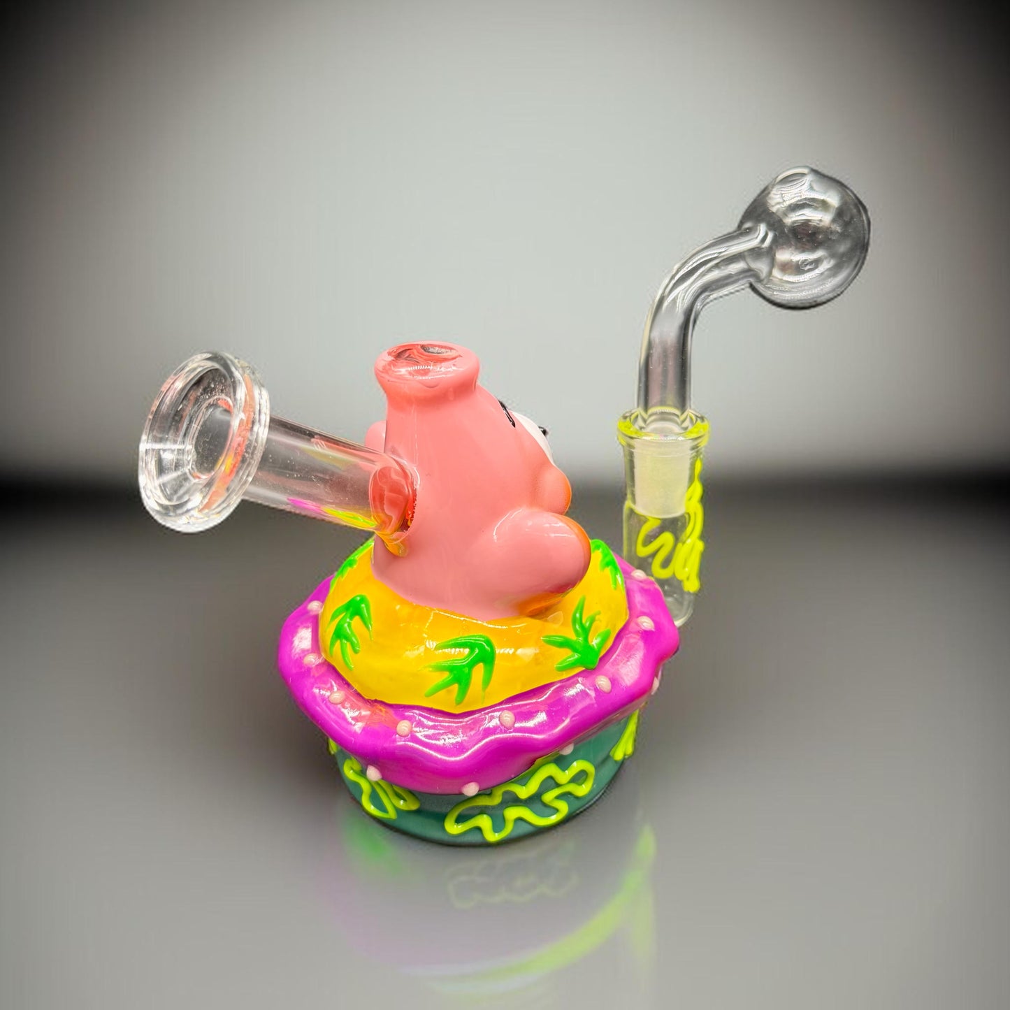 Colorful glass smoking device with a pig design on a gray background