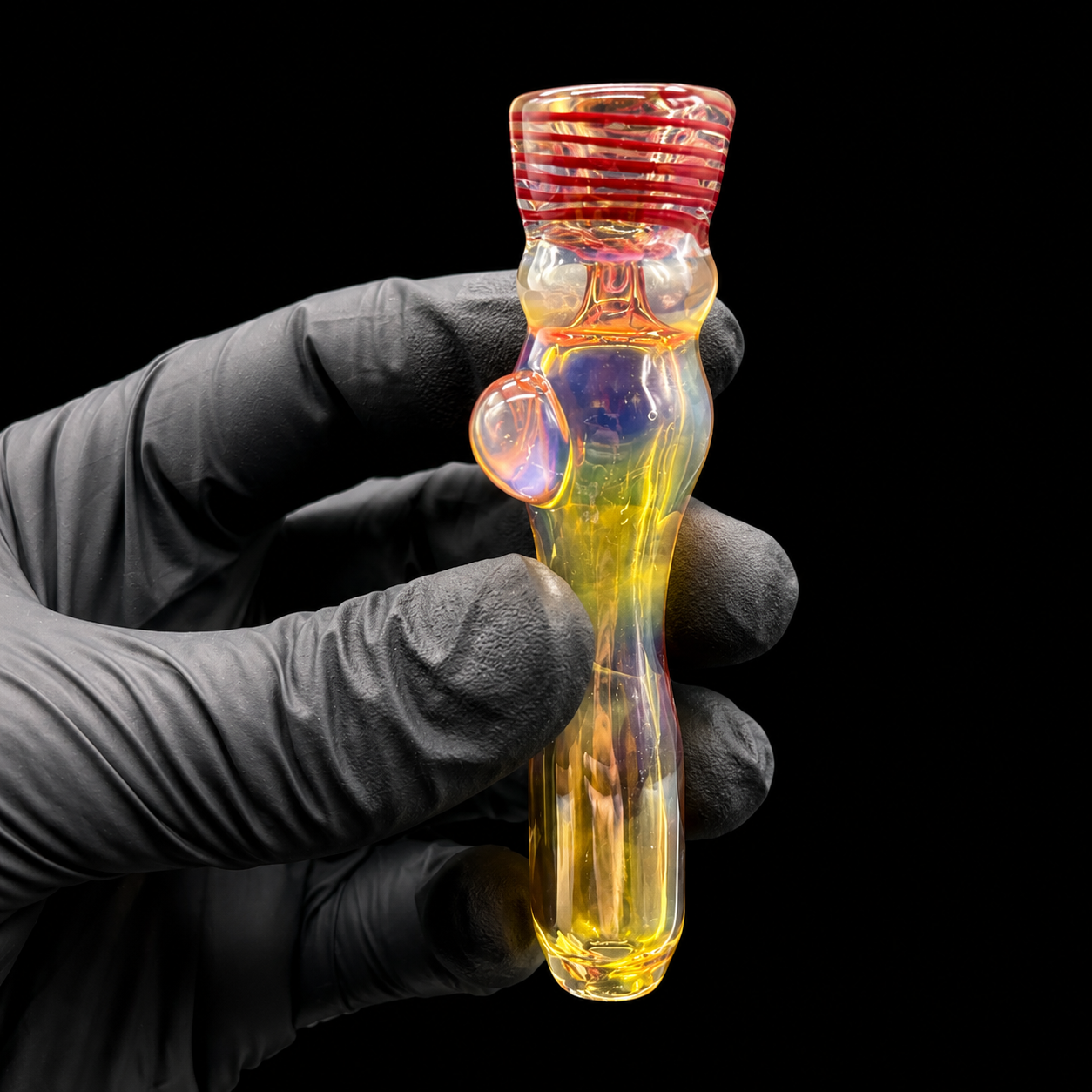 Glass smoking device held by a gloved hand against a black background