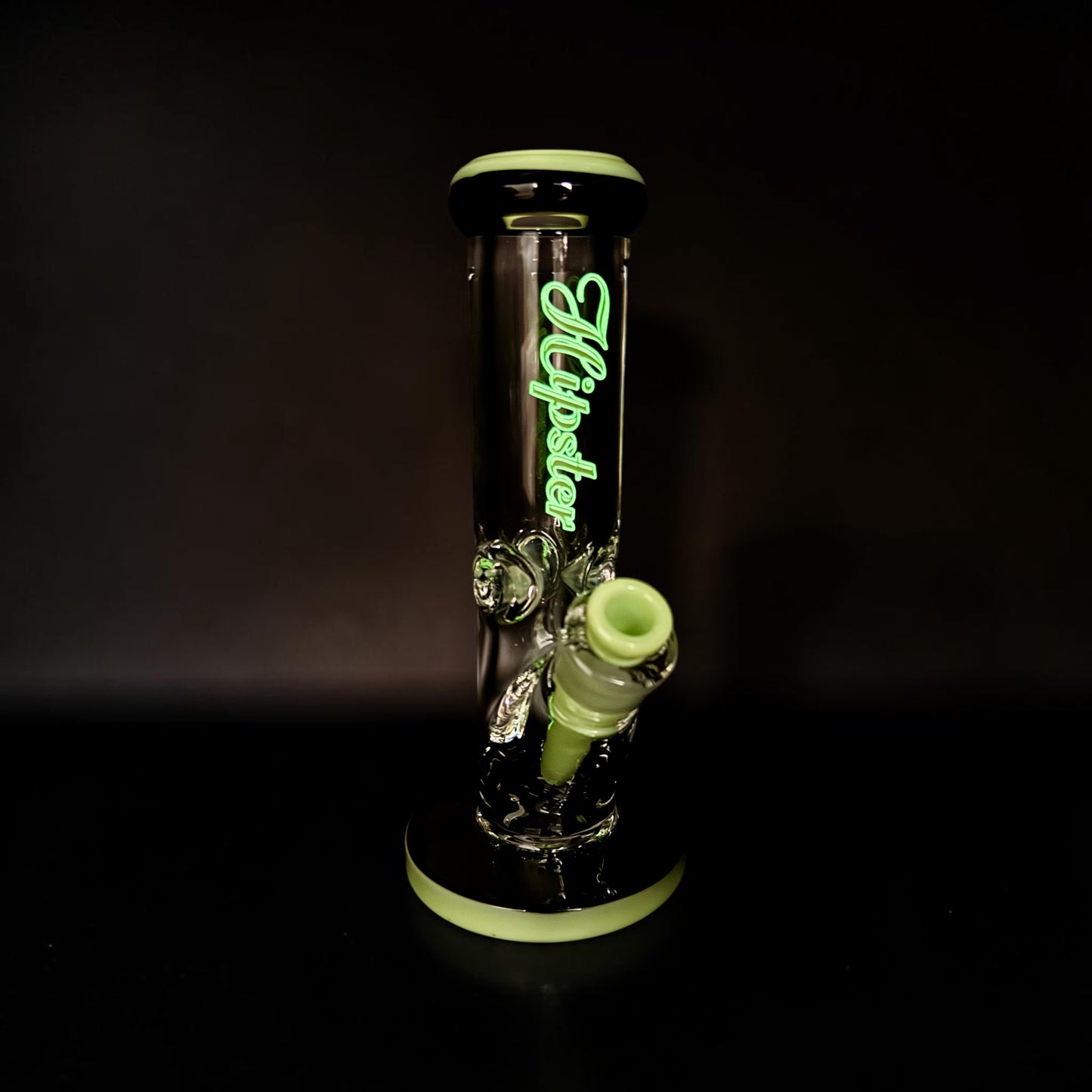 Glass water pipe with green accents on a black background