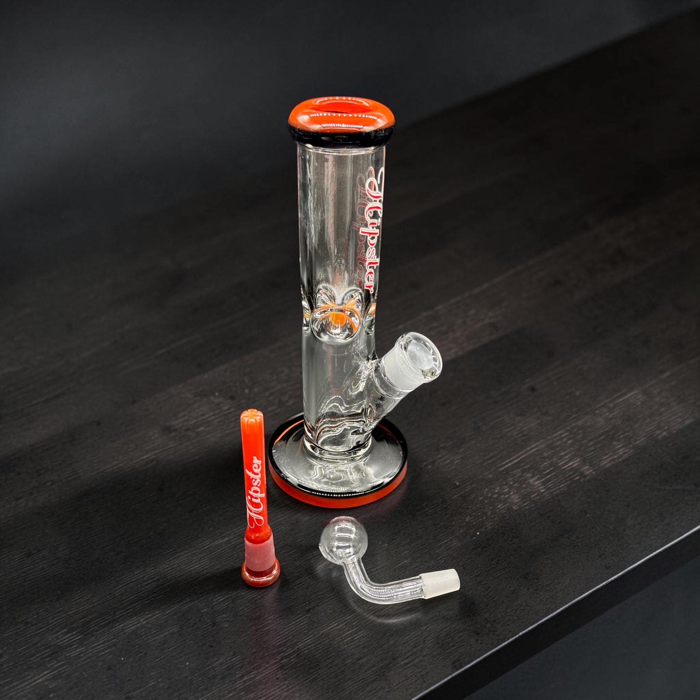 Glass water pipe with red accents on a dark surface