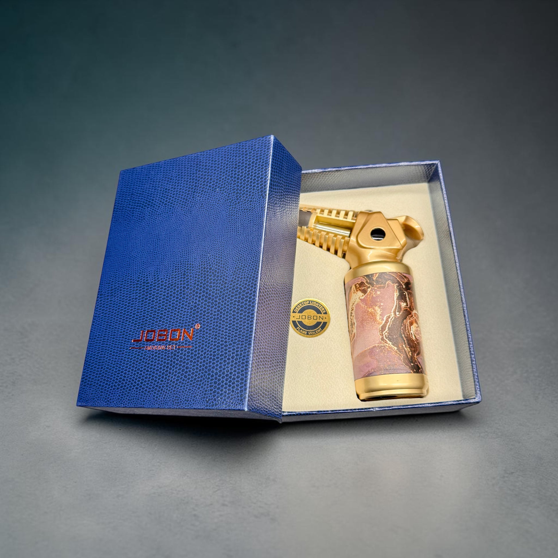 Gold lighter with marbled design in a blue box on a gray background
