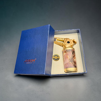 Gold lighter with marbled design in a blue box on a gray background