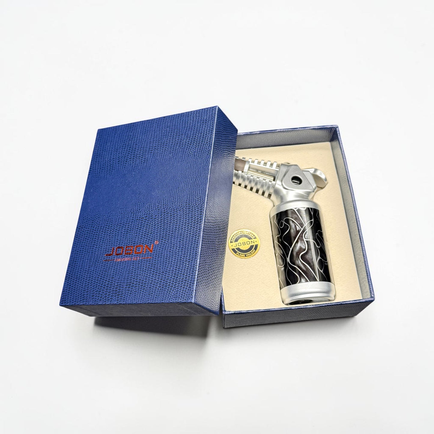 Silver and black bottle with decorative design in a blue box, featuring the Jogan brand.