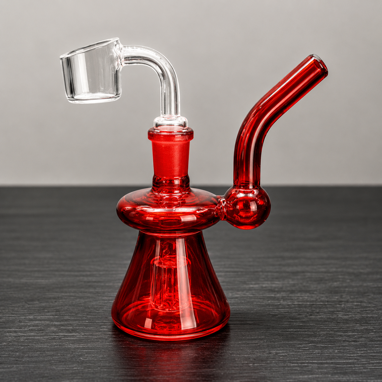 Red glass smoking device on a dark surface with a gray background