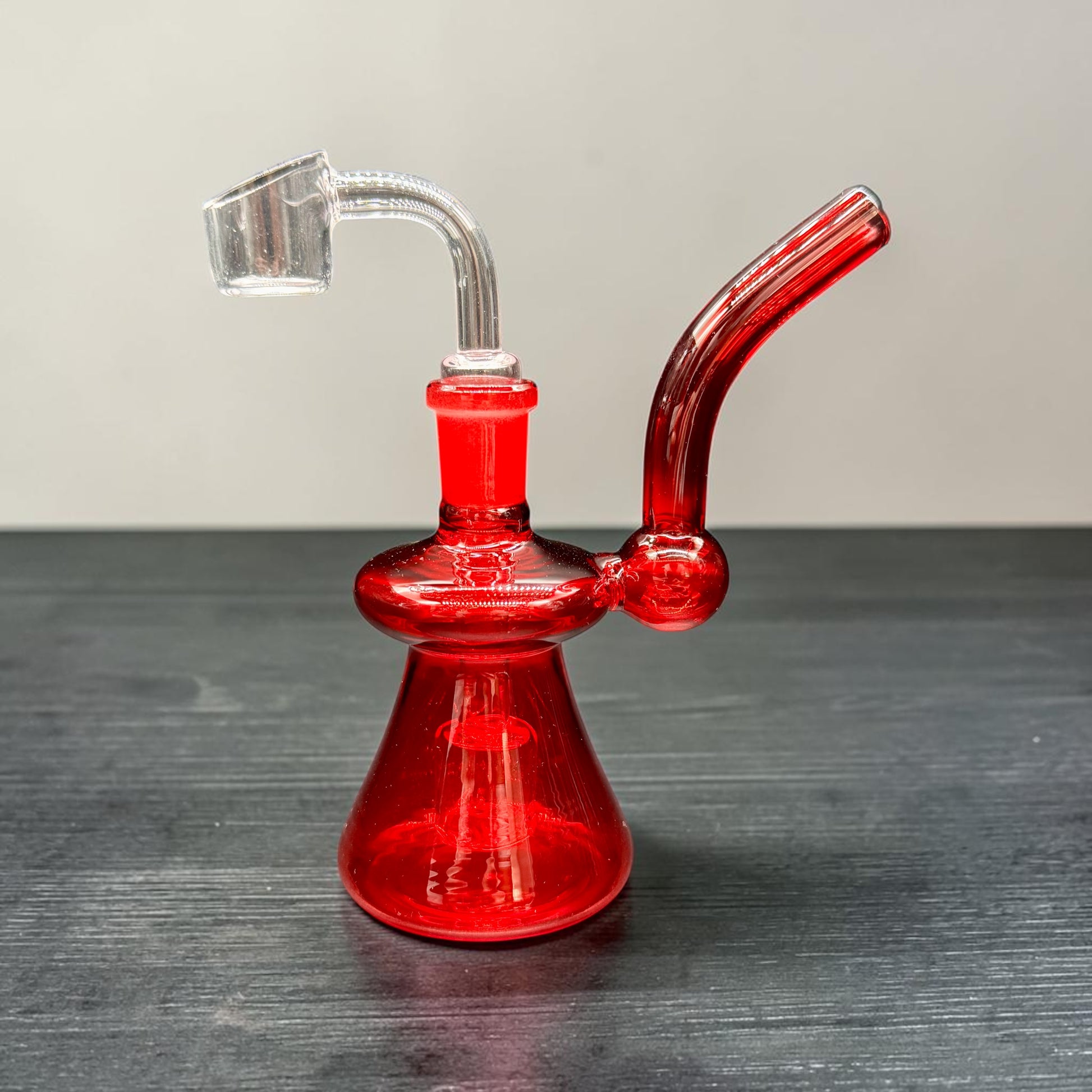 Red glass water pipe on a dark surface with a gray background