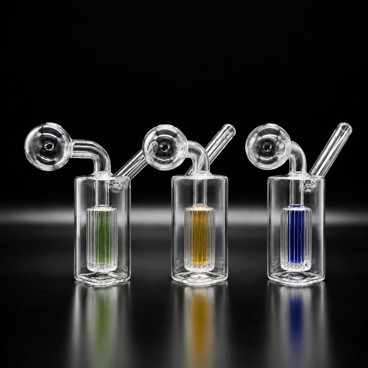 Three glass smoking devices with colored liquids on a black background