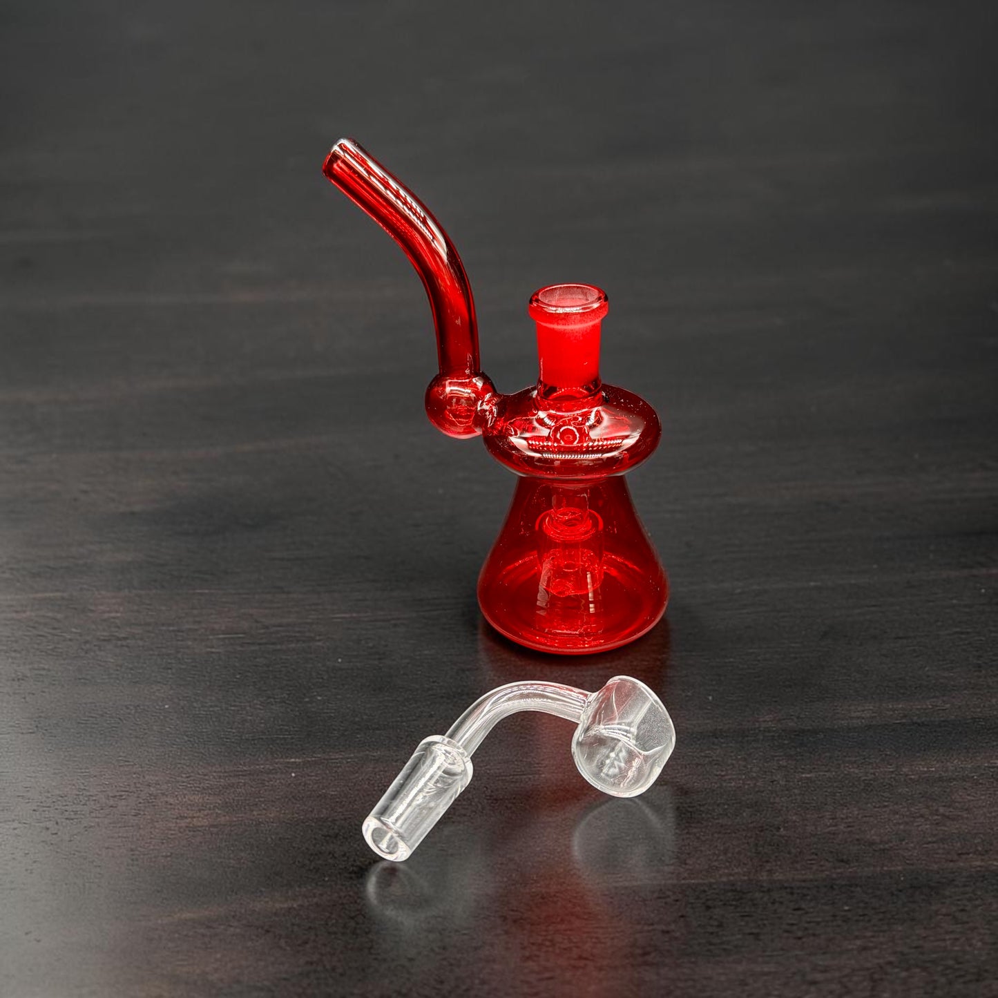 Red glass smoking device on a dark wooden surface