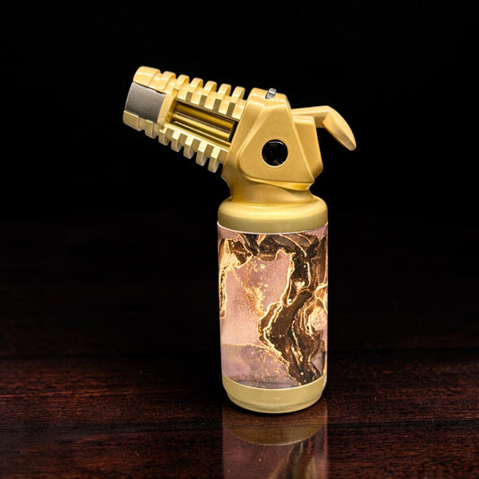 Gold torch lighter with a decorative base on a dark surface