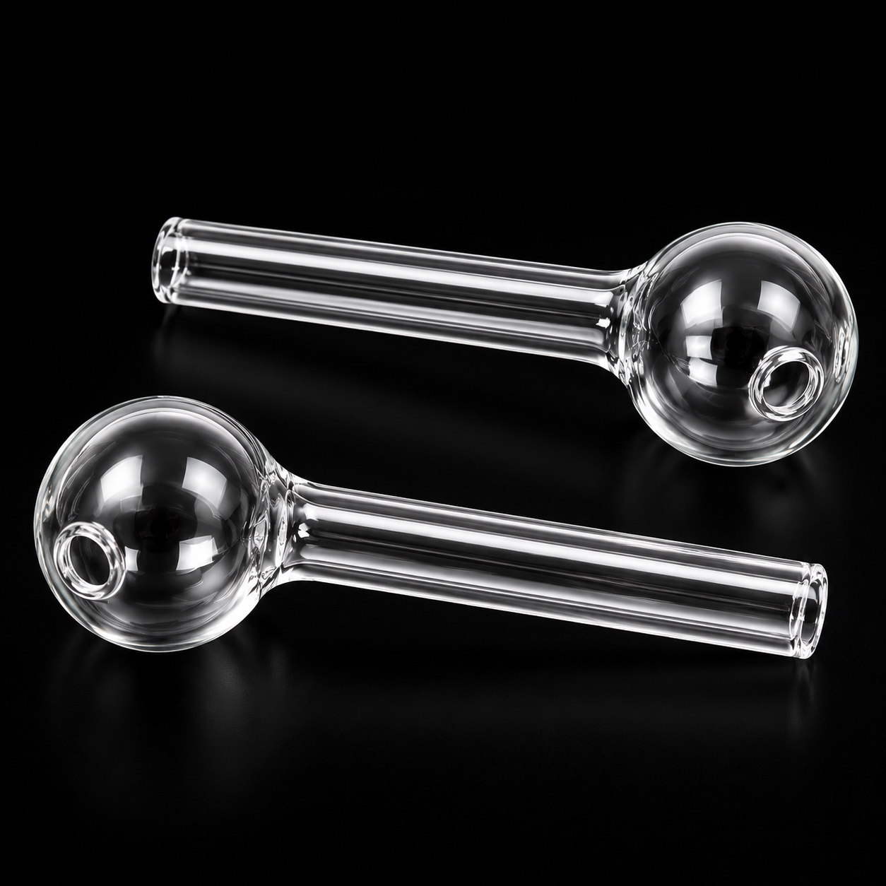 Two clear glass smoking pipes on a black background