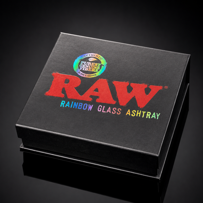 A black square box for a RAW brand rainbow glass ashtray, featuring a large red RAW logo and multicolor text on a dark reflective background.